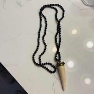 Black faceted beaded necklace and a cream tusk pendant with a gold-tone cap